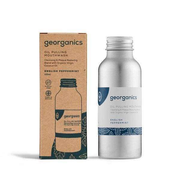 Georganics Piparminttu Oil Pulling Purskutteluöljy -pullo pakkauksensa vieressä; ruskea, mattapintainen pahvipakkaus ja sylinterimäinen, harjattu metallipullo kierrekorkilla; molemmissa minimalistiset etiketit tekstausvapaalla kirjasimella; teksti mainitsee ekologisen pakkauksen; kuvattu tasaisesti valaistuna, ei ihmisiä tai muita esineitä.