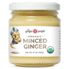 The Ginger People luomu murskattu inkivääri; kirkas lasipurkki metallikannella, valkoisessa etiketissä sarjakuvamainen inkiväärihahmo ja USDA Organic -sertifiointimerkki; lihavoitu, sekakirjaiminen groteskiteksti tuotenimestä; valkoinen tausta.