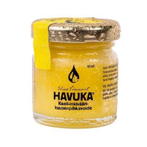 Havuka Kaali-Inkivääri Kuusenpihkavoide; pieni lasipurkki Havuka-voidetta keltaisella mattaetiketillä ja yhteensopivalla kierrekannella, molemmat peittyneinä näkyvillä kondensaatiopisaroilla; kirkas lieriömäinen astia sisältää eloisan keltaista voidetta; etiketissä suomenkielistä tekstiä tummin groteskikirjaimin; ei ihmisiä tai käsiä; kuvattu neutraalia taustaa vasten.