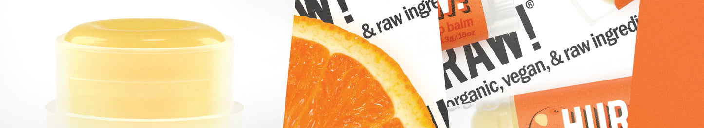 Hurraw! Huulivoide Appelsiini -tuubi, keltainen, mattapinta, vieressä pakkaus appelsiiniviipalekuvituksella ja tekstillä "RAW! Organic, vegan, & raw ingredients" isoin versaalikirjaimin