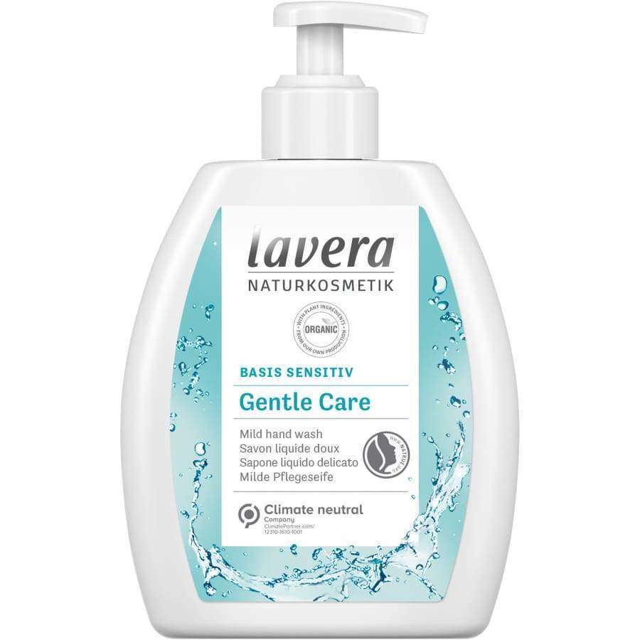 Lavera Naturkosmetik Gentle Care Mild Hand Wash -käsipesu; valkoinen ja sininen pumppupullo vesiroiskekuvituksella ja tuotetiedoilla etiketissä; lieriömäinen muovipullo kiiltävällä pinnalla, vaaleansininen pumppu; etiketissä "Lavera Naturkosmetik" lihavoidulla groteskifontilla; ei ihmisiä tai käsiä; vaalea tausta, suoraan edestä kuvattu studiokuva.
