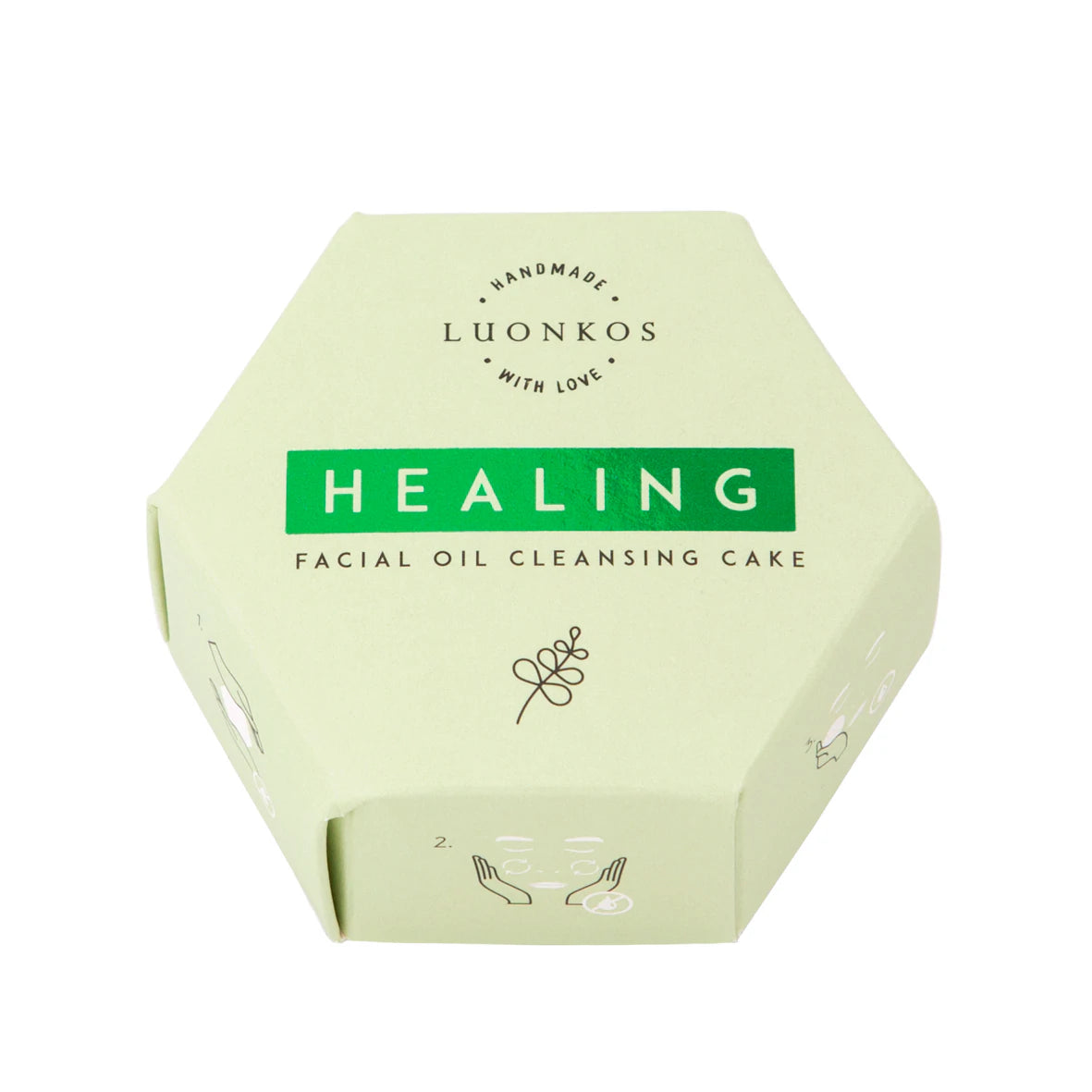 Luonkos Healing Facial Oil Cleansing Cake -pakkaus, vaaleanvihreä kuusikulmainen rasia mattapahvia, kaksi puolta koristeltu yksinkertaisin mustin viivapiirroksin käsistä ja lehdistä; teksti "Luonkos Handmade With Love Healing Facial Oil Cleansing Cake" suuraakkosin tummalla tekstausvapaalla fontilla; pakkaus kuvattu yksinään vaaleaa taustaa vasten tasaisessa valaistuksessa; ei ihmisiä tai käsiä näkyvissä.
