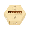 Luonkos Rebirth Facial Oil Cleansing Cake -kuusikulmainen laatikko, yksinkertaisin kasvonpesukuvituksin, kaakaopapukuvake ja vaaleanbeige pakkaus; pakkaus mattapinnalla tummalla tekstillä ja viivagrafiikoin; typografia siistiä ja tekstausvapaata; ei ihmisiä tai käsiä näkyvissä; kuva yksinkertaisella taustalla, ei muuta rekvisiittaa näkyvissä.