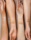 Madara City CC-voide SPF15 Tan; kolme eri ihonsävyistä käsivartta näyttää neljä meikkivoidenäytettä nimillä vaalea, beige, keskitumma ja tan neutraalilla taustalla, havainnollistaen sävyvalikoiman monimuotoisuutta eri ihonvärien kesken; näytteet suorina viivoina käsivarsien sisäpinnalla; etiketit painettu suoraan kunkin näytteen ylä- tai alapuolelle yksinkertaisella groteskikirjasimella; ei pakkausta näkyvissä, rajattu kuva keskittyen käsivarsiin ja käsiin.