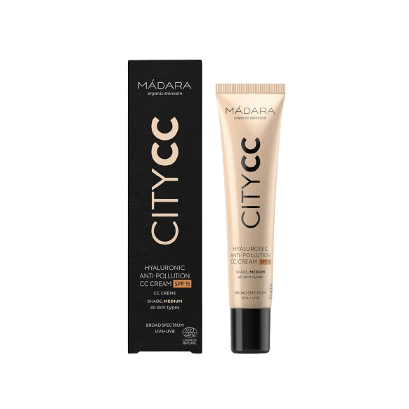 Madara City CC-voide SPF15 Medium -tuubi mustan ja kultaisen laatikkopakkauksen vieressä, molemmat pystyssä valkoisella taustalla; tuubi sylinterimäinen mattapinnalla, laatikossa kiiltävän mustia ja metallisen kultaisia osioita; molemmissa tekstausvapaata typografiaa valkoisella tai kultaisella; ei ihmisiä tai käsiä näkyvissä.