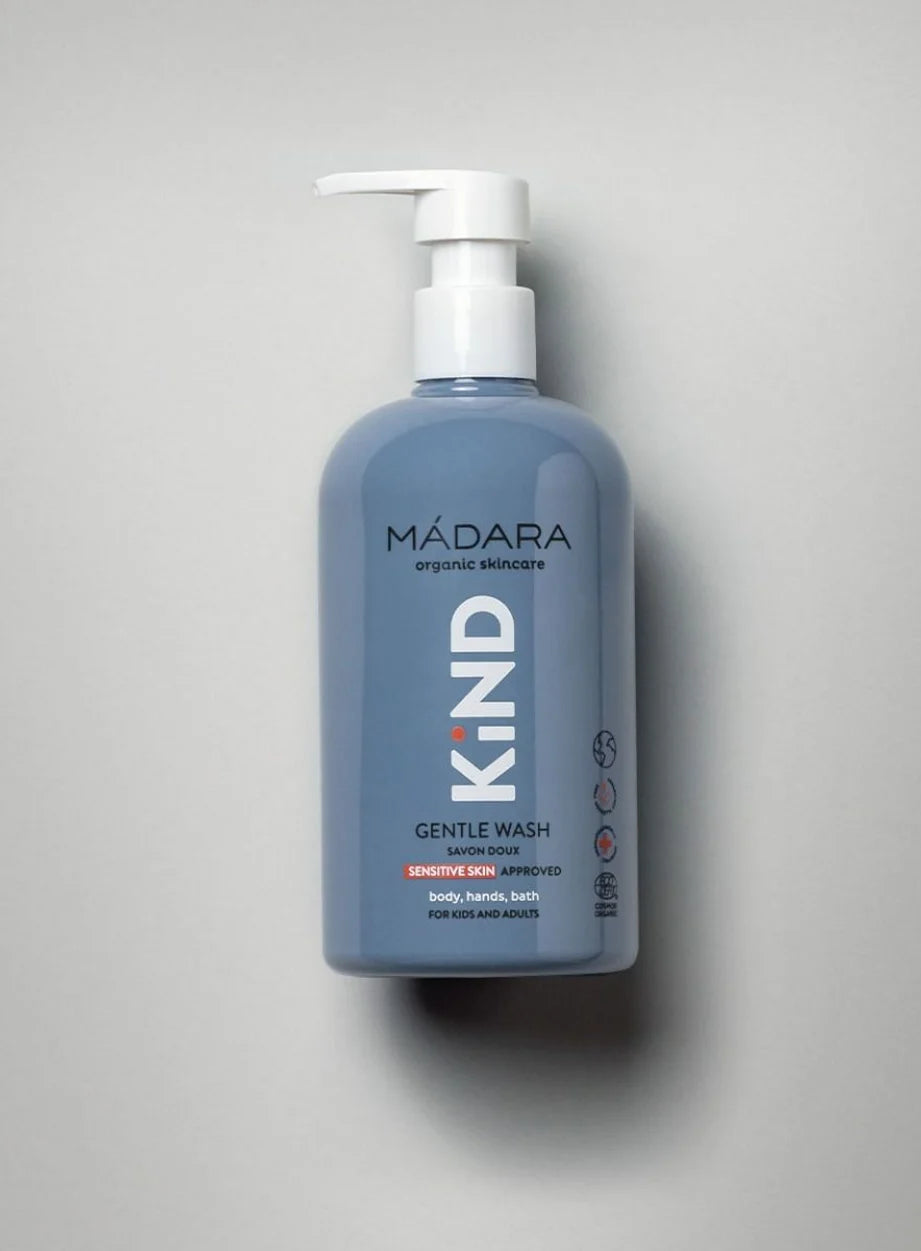 Madara KIND Gentle Wash hellä pesuaine; sininen, mattapintainen pumppupullo pystyssä; etiketissä valkoista ja vaaleanharmaata groteskitekstiä herkälle iholle sopivasta, rauhoittavasta kaavasta käytettäväksi vartalolle, käsille ja kylpyyn, suunniteltu erityisesti lapsille ja vauvoille; valkoinen tausta, tuote keskellä.