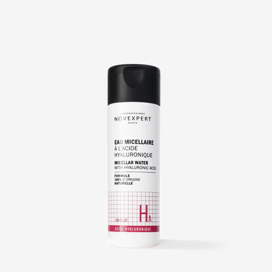 Novexpert HYALURONIC Micellar Water; pullo mustalla korkilla ja valkoisella etiketillä pystyssä valkoisella taustalla; teksti mustalla ja vaaleanpunaisella kertoo hyaluronihaposta ja kosteuttavista ominaisuuksista; pullo sylinterinmuotoista muovia kiiltäväpintaisena; brändinimi versaalikirjaimin groteskikirjasimella, lyhyt tuotekuvaus alla; ei ihmisiä tai käsiä kuvassa.
