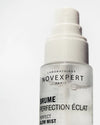 Novexpert POLYPHENOLS Perfect Glow Mist; lähikuva kirkkaasta, lieriön muotoisesta suihkepullosta pyöristetyin hartioin ja läpikuultavalla korkilla valkoisella taustalla; kiiltäväpintainen, mustaa ja metallista vaaleanpunaista groteskitekstiä "Laboratoires Novexpert Paris Brume Perfection Éclat Perfect Glow Mist".