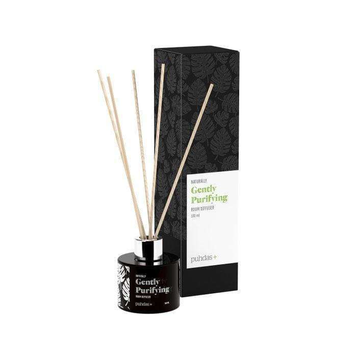 puhdas+ Naturally Gently Purifying -huonetuoksuttimen pullo, musta, sekä luonnolliset puiset tuoksukepit; pullo lieriömäinen ja mattapintainen; pakkaus vieressä, mustavalkoinen lehtikuvio, mattapinta, suorakulmainen muoto ja sana "natural"; molemmat neutraalilla taustalla; ei ihmisiä tai käsiä; studiokuva silmän tasolta.