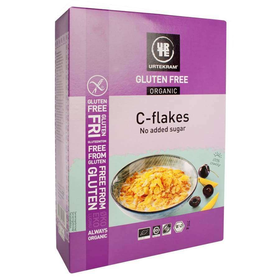 Urtekram Gluteeniton Luomu Corn Flakes -pakkaus, violetti, kuva kulhollisesta maissihiutaleita hedelmien kera; mattapintainen suorakulmainen rasia, groteskiteksti "No added sugar", "Always organic", gluteeniton