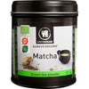 Urtekram Luomu Matcha-tee -metallipurkki, 50 g; musta, sylinterimäinen ja mattapintainen purkki sopivalla kannella; etiketissä kuva vihreää jauhetta sisältävästä kulhosta ja bambuvispilästä sekä vihreitä ja valkoisia värielementtejä, mukaan lukien EU:n luomusertifiointimerkki; lihavoitua valkoista tekstausvapaata tekstiä; kuvattu valkoista studiotaustaa vasten, ei ihmisiä tai käsiä näkyvissä.