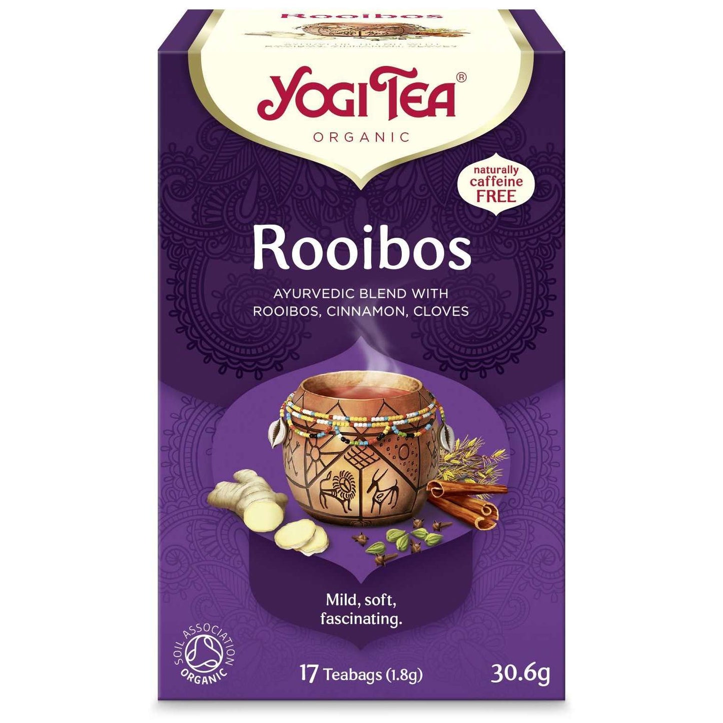 YogiTea Luomu Rooibos tee; violetti Yogi Tea Organic Rooibos -rasia kuvitetulla mukilla ja eloisin mausteinen; pakkaus korostaa kofeiinittomuutta ja sisältää 17 teepussia; mausteita kuten kanelia ja inkivääriä kuvattu pakkauksessa; suorakulmainen pahvipakkaus mattapinnalla, painettua serif- ja groteskitekstiä; ei näkyviä käsiä tai ihmisiä, valokuvattu neutraalia taustaa vasten studioympäristössä.